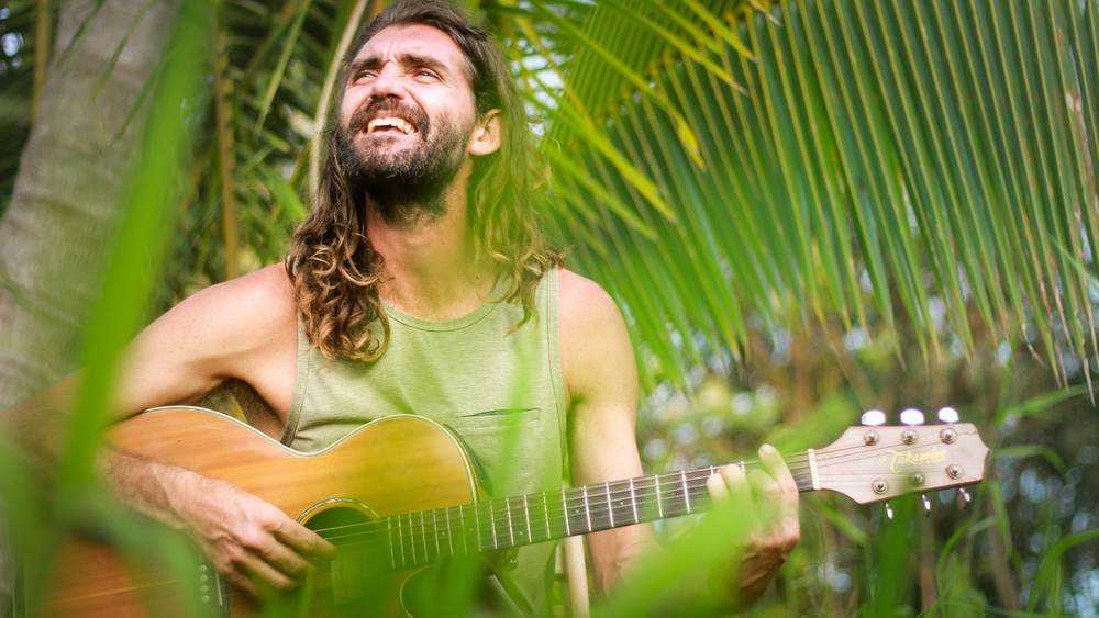 Musician playing guitar under palm trees